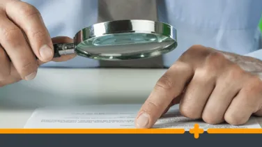 Osoba czytająca dokument i sprawdza zapisy umowy pod lupą